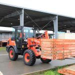 A orange truck carrying crates outside an industrial building